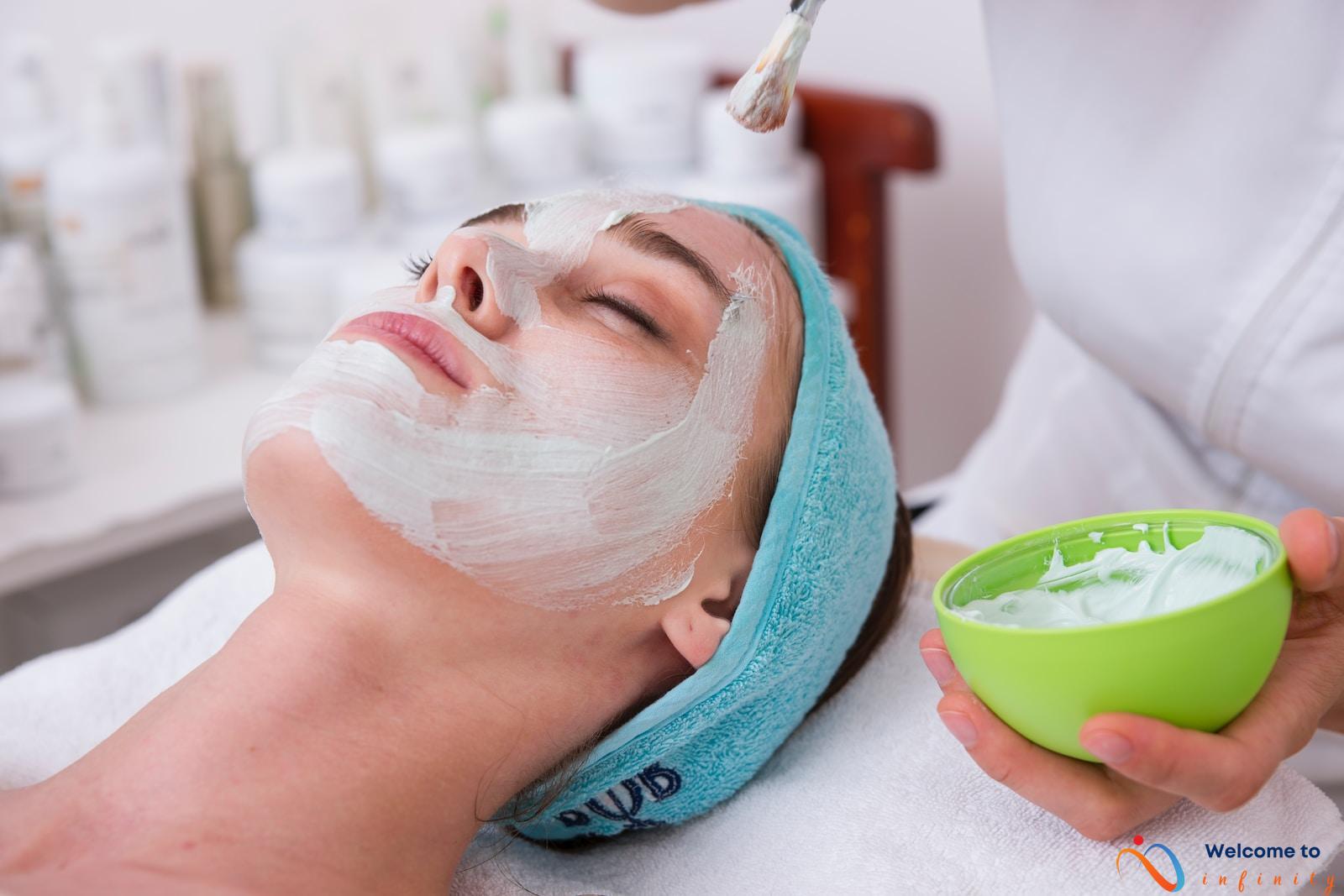 woman lying on blue towel with white cream on face